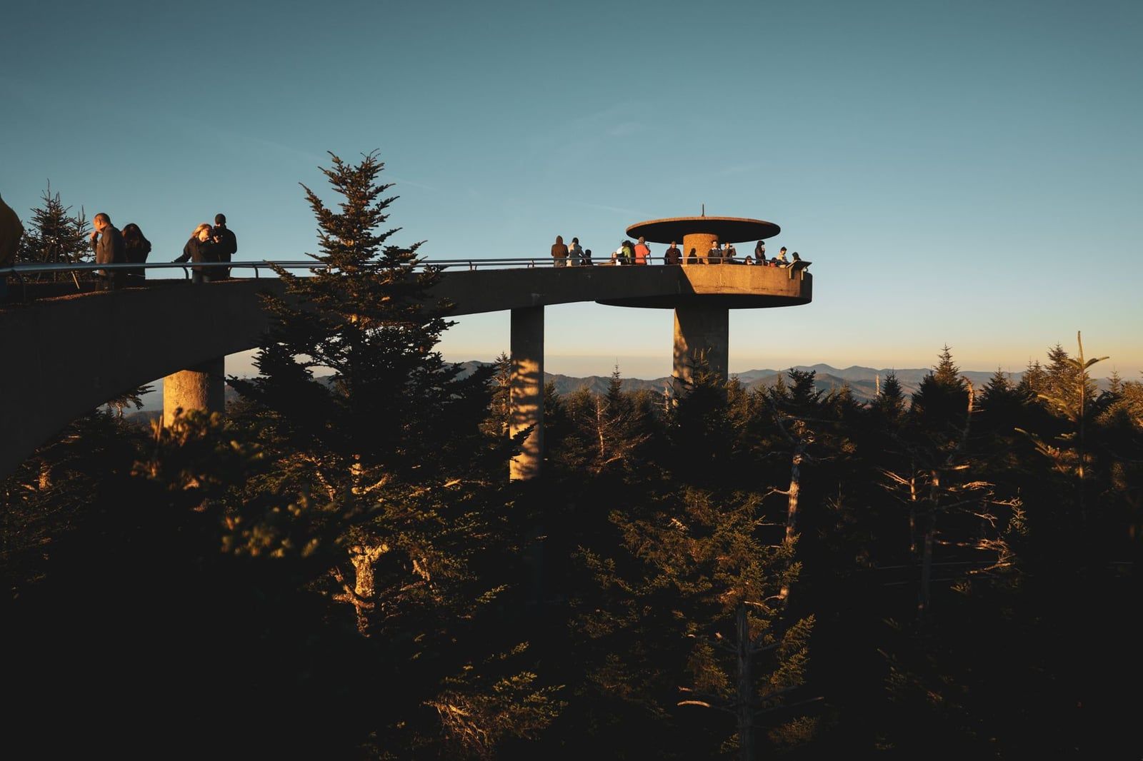 Visitors stand on the concrete observation tower and elevated walkway at Clingmans Dome in Great Smoky Mountains National Park during twilight.