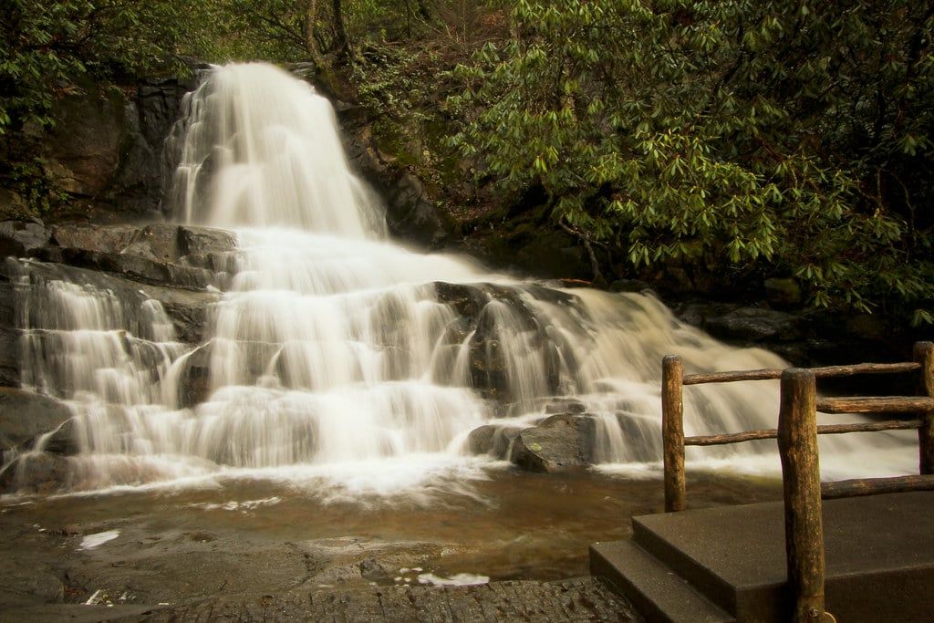 Water cascades over rocky ledges at Laurel Falls next to a wooden-railed footbridge in Great Smoky Mountains National Park.