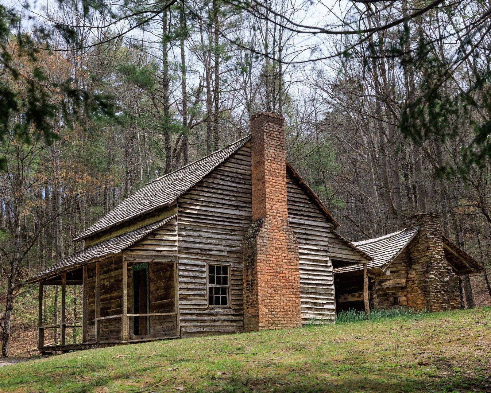 The historic 19th-century Henry Whitehead log cabin and brick chimney stand in Cades Cove at Great Smoky Mountains National Park.